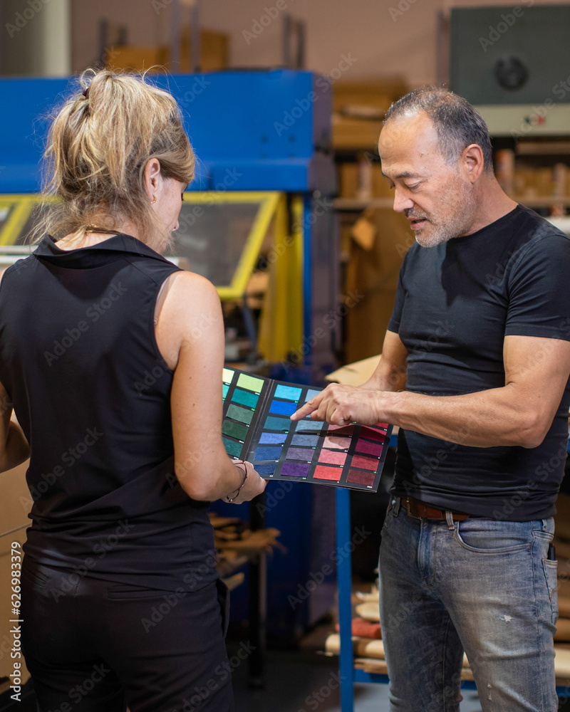 Serious middle aged man choosing colorful fabric samples with anonymous woman in daylight Serious middle aged man choosing colorful fabric samples with anonymous woman in daylight