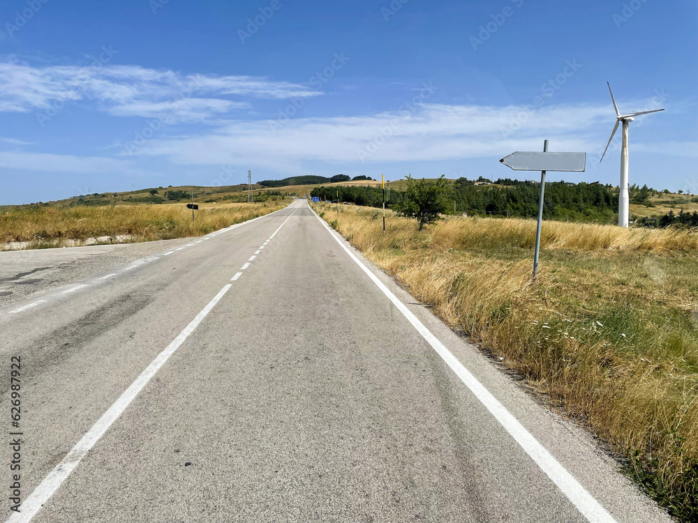 country road with wind turbines on the sides