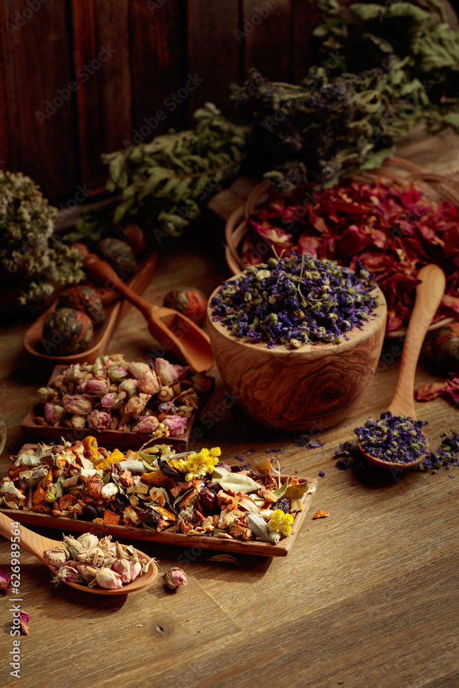 Various dried medicinal plants, herbs, and flowers on an old wooden background.