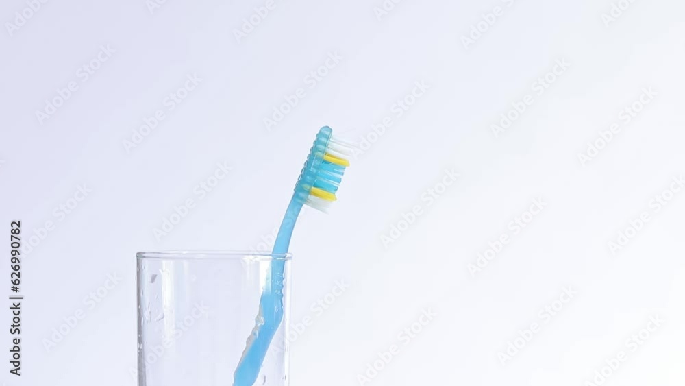 Oral hygiene. Toothbrushes in a glass on a light background. A woman's hand takes a toothbrush, close-up. Brush your teeth Oral hygiene. Toothbrushes in a glass on a light background. A woman's hand takes a toothbrush, close-up. Brush your teeth
