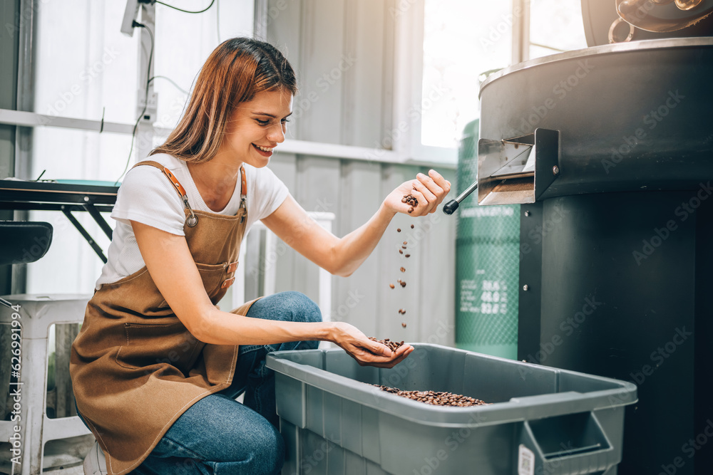 Obraz premium Professional Coffee Roaster Woman, Barista Checking Quality and Aroma of Roasted Coffee Beans From Machine in Factory.