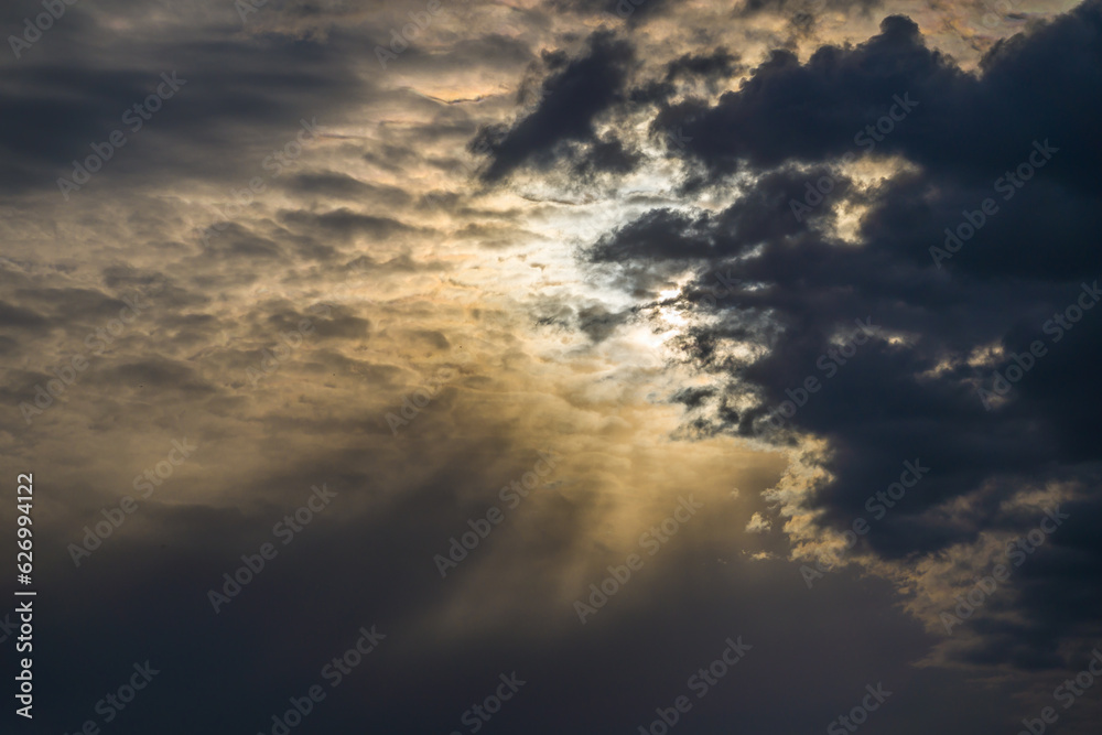 Naklejka premium Dark ominous clouds at bright sunset, sun beams