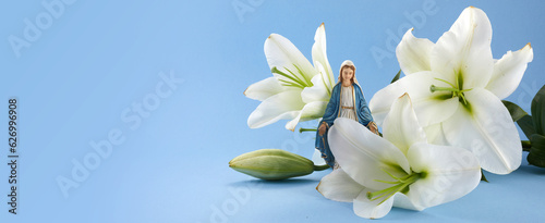 Assumption of Mary day. Virgin Mary figurine with lily flowers. photo