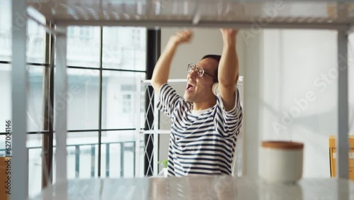 greeting happiness joyful asian adult male wearing casual cloth and wirreless headphone dance music lover while unpack stuff relax from home moving house relocation ,he is happy to move in new house photo