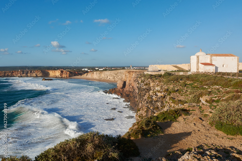 Sagres Fortress on the edge of the cliffs, Portugal. Stormy ocean and Praia do Tonel in the background