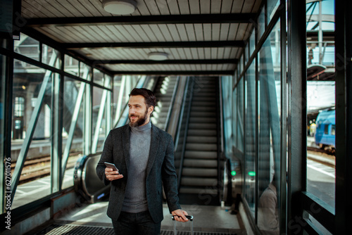 Young man using a smart phone while on an escalator at the train station © Geber86