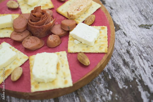 Cheese, Crackers, Sausage, and Almond nuts platter. Cheese plater on wooden plate for breakfast and snacking.