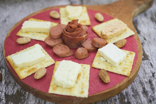 Cheese, Crackers, Sausage, and Almond nuts platter. Cheese plater on wooden plate for breakfast and snacking.