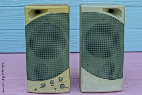 two old plastic speakers with a speaker small powerful electronic stereo gray speakers for an old computer stand on a pink wooden table photo