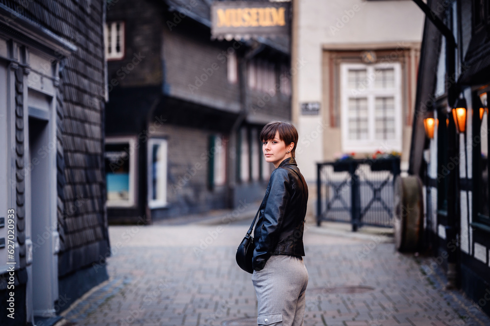 Young woman in black leather jacket with short dark hair walking on street