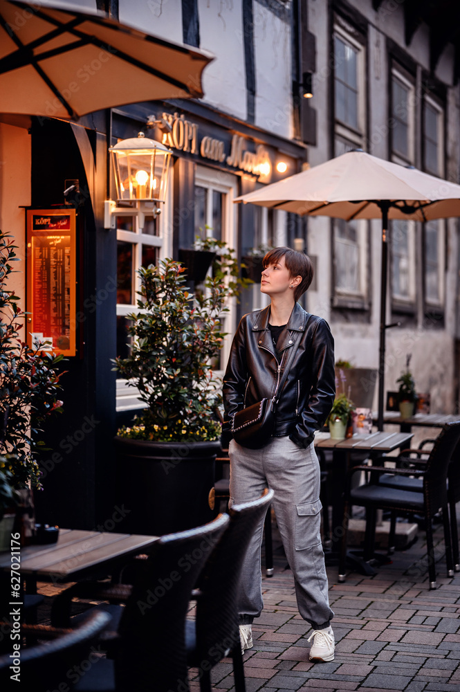 Young woman in black leather jacket with short dark hair standing in german city Young woman in black leather jacket with short dark hair standing in german city