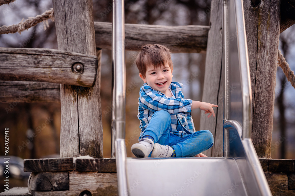 Little toddler boy in blue shirt trying to climb down a wooden ladder on playground Little toddler boy in blue shirt trying to climb down a wooden ladder on playground