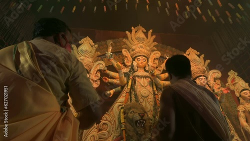 Howrah, West Bengal, India - 3rd October, 2022 : Hindu Priests worshipping Goddess Durga with white conch shell. Ashtami puja aarati - sacred Durga Puja ritual - fetival of Hinduism, at night. photo