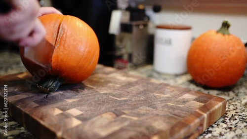 Cutting a small round pumpkin on a wooden board
