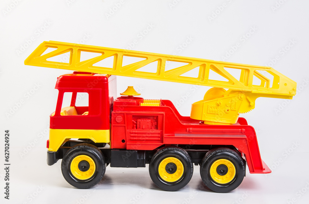 Multi-colored plastic toy trucks for children's games on a white background. Red fire truck with telescopic antenna.
