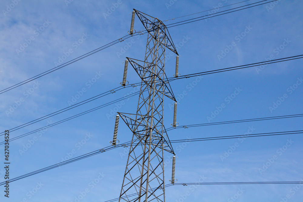 Tall metal pylon reaching up into the blue sky transmitting electricity through the cycles and wires. Tall metal pylon reaching up into the blue sky transmitting electricity through the cycles and wires.