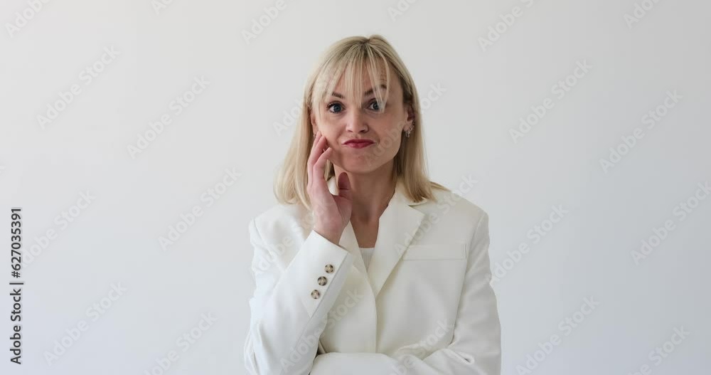 A blonde woman is seen facepalming on a white background. With a hand brought to her face in frustration or disbelief, she expresses a classic facepalm gesture. A blonde woman is seen facepalming on a white background. With a hand brought to her face in frustration or disbelief, she expresses a classic facepalm gesture.