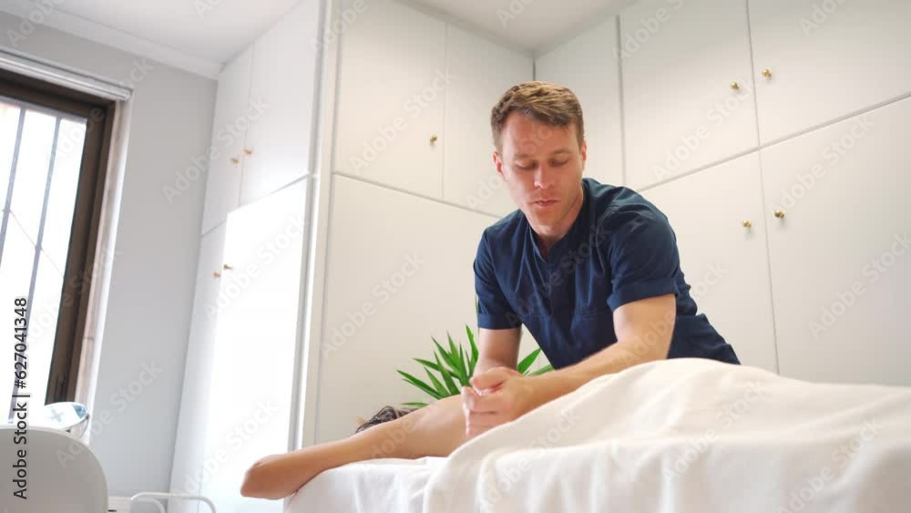 Medium shot of male massager giving therapeutic and relaxing, deep tissue stimulating back massage to a Caucasian female patient Medium shot of male massager giving therapeutic and relaxing, deep tissue stimulating back massage to a Caucasian female patient