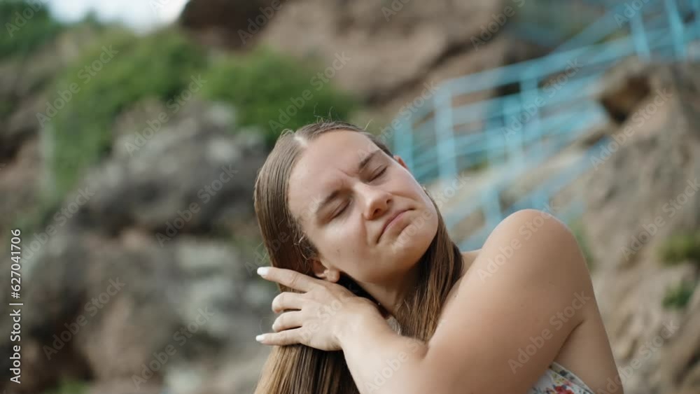 Against the backdrop of a blue staircase descending to the sea along the cliff, a young woman combs her wet hair. Slow motion. Against the backdrop of a blue staircase descending to the sea along the cliff, a young woman combs her wet hair. Slow motion.