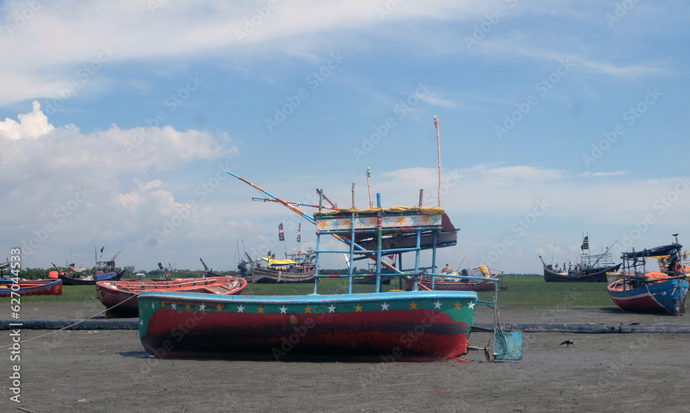 Fototapeta premium Fishing boats are waiting for the tide.So the fishermen are repairing the nets sitting in boat.Fishermen will go to the sea and catch the popular fish Hilsa.