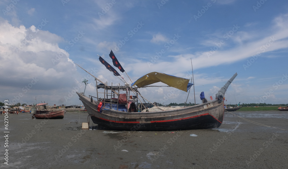 Fishing boats are waiting for the tide.So the fishermen are repairing the nets sitting in boat.Fishermen will go to the sea and catch the popular fish Hilsa.