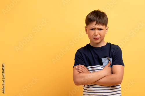 фотографія Angry offended school aged boy with hands crossed on chest