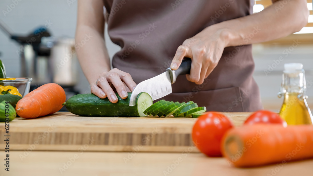 Woman cutting vegetables, cucumber ready for cooking. Woman cutting vegetables, cucumber ready for cooking.