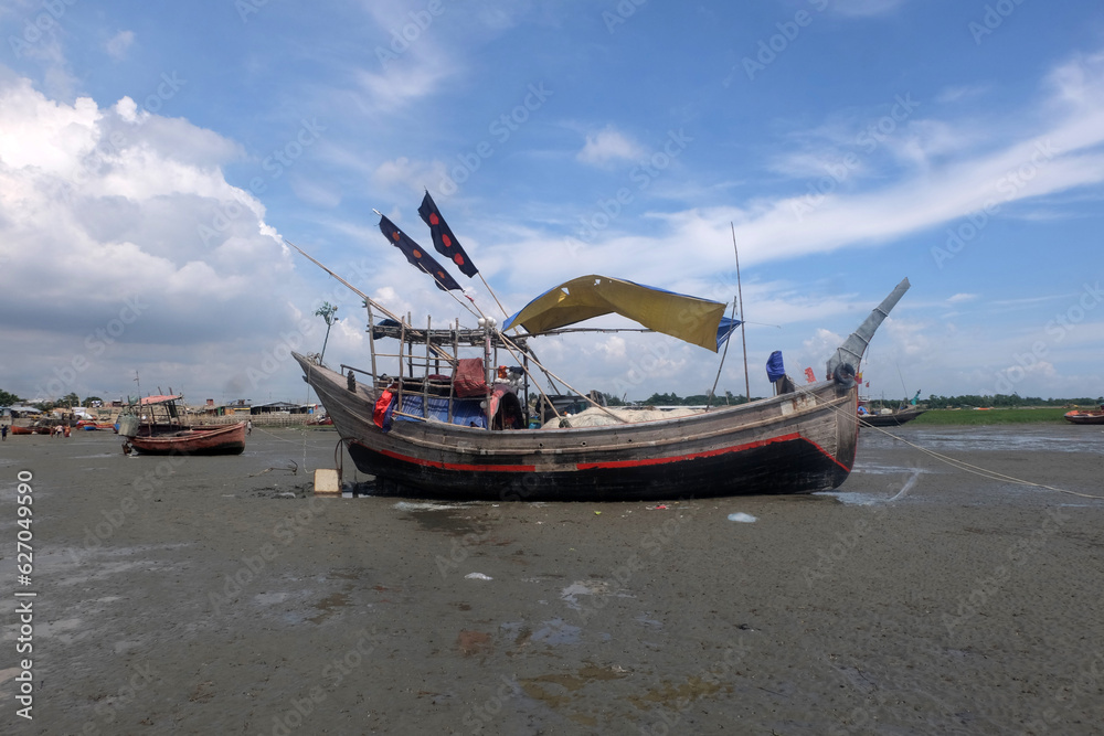 Fishing boats are waiting for the tide.So the fishermen are repairing the nets sitting in boat.Fishermen will go to the sea and catch the popular fish Hilsa.