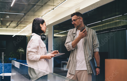 Focused colleagues standing and speaking in office