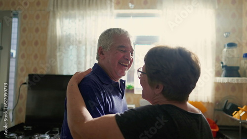 Elderly Couple Dancing in Morning Light by Kitchen Window, Senior Husband and Wife in Loving Embrace