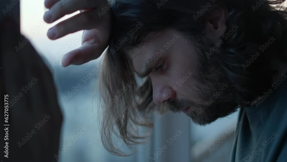 Stressed, depressed man staung near window, looking down with frustrated eyes. Midlife crisis in men, person in crisis concept. Tired aphaty man portrait Life problems and male middle age crisis.  