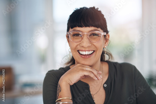 This is the smile of success. Cropped portrait of an attractive young businesswoman sitting alone in her office with her hand on her chin.
