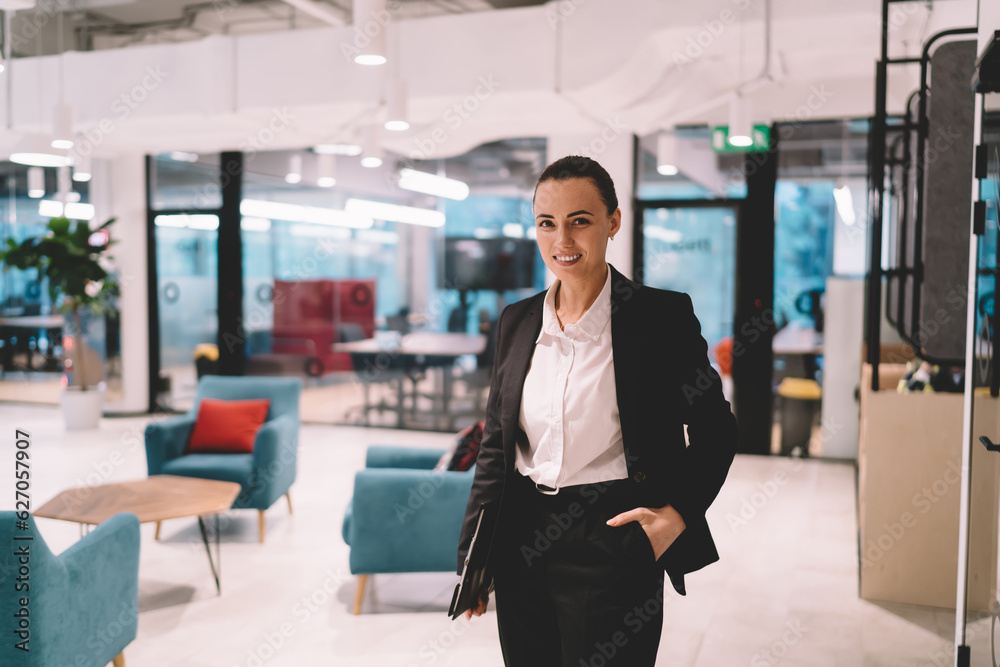 Smiling businesswoman in formal suit standing in modern office