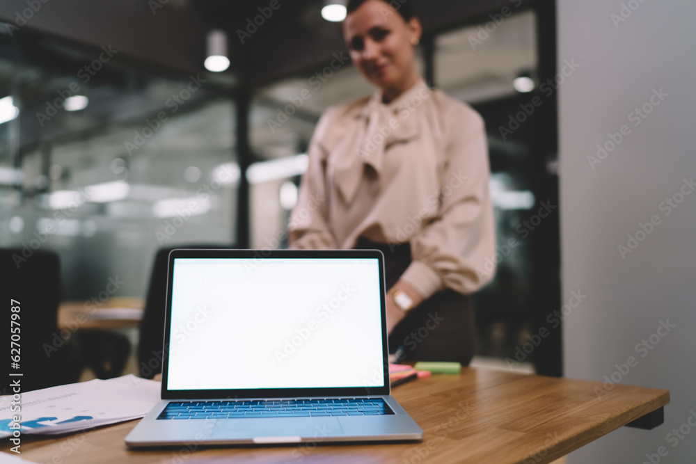 Smiling woman standing near laptop in office Smiling woman standing near laptop in office