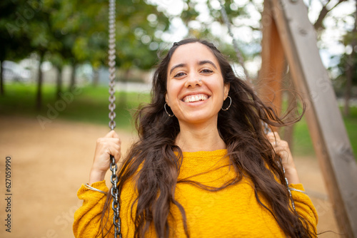 Close up happy young woman on swing in park