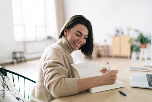 Cheerful woman taking notes in diary