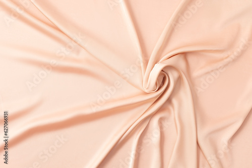 Silk background in peach color with folds in the form of a rose photo