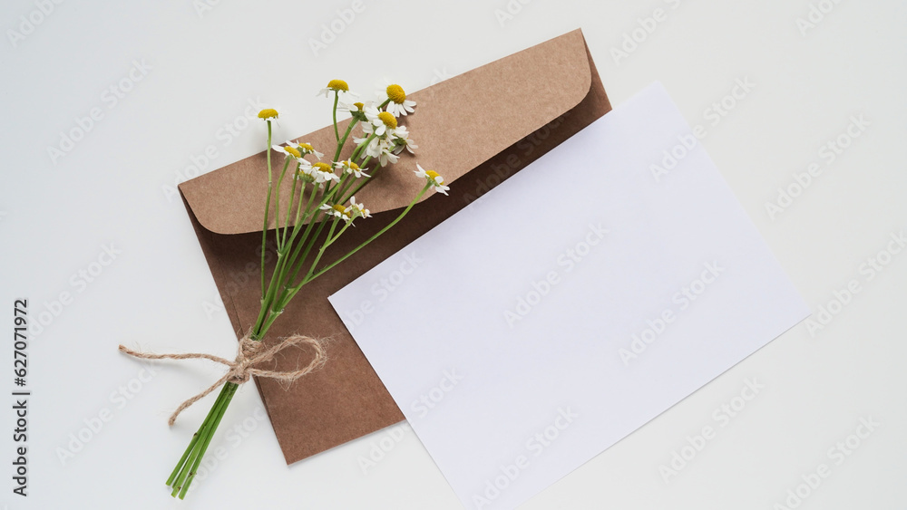 Minimal composition,mockup for greeting card or holiday invitation,flat lay,copy space.Brown craft envelope,blank card for text,chamomile branch.Wedding invitation,christening,birthday,love letter. Minimal composition,mockup for greeting card or holiday invitation,flat lay,copy space.Brown craft envelope,blank card for text,chamomile branch.Wedding invitation,christening,birthday,love letter.
