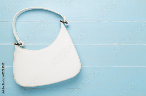 Trendy woman bag on wooden background, top view