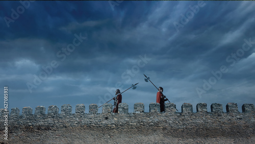 Canvas Print Roman guards with spears on a citadel wall at night.