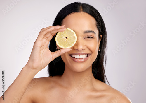 Happy woman, portrait and lemon for natural vitamin C, citrus or healthy nutrition against a grey studio background. Face of female person with fruit in skincare, collagen or antioxidant for diet