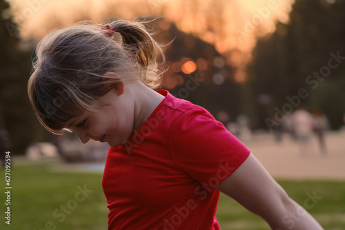 A ten - year - old girl runs through the park at sunset . The child is engaged in sports . Healthy lifestyle . photo