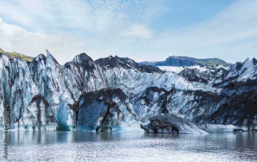 Solheimajokull picturesque glacier in southern Iceland. The tongue of this glacier slides from the volcano Katla. Beautiful glacial lake lagoon with blocks of ice and surrounding mountains.