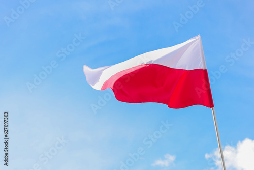 The national flag of Poland in the daytime on the background of the blue sky