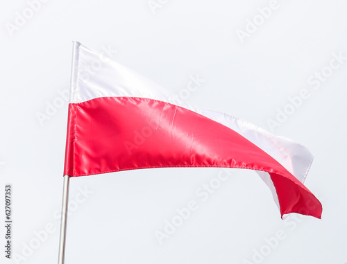 The national flag of Poland in the daytime on the background of the blue sky