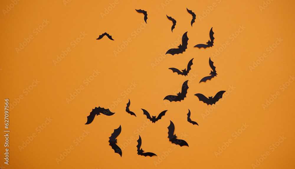 Halloween holiday concept. Black paper bats on bright orange background, top view, flat lay,copy spaes.Celebration of the dead