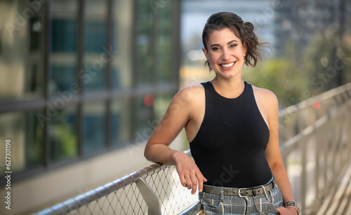 Modern lifestyle portrait of a friendly woman with a charming smile, smiling in downtown urban background with copy space