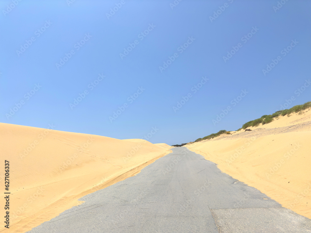 view of the road in the middle of a sandy dune landscape that looks like a desert, Duna de Valdevaqueros, Dunes of Valdevaqueros, Tarifa, Costa de la Luz, Cadiz, Andalusia, Spain