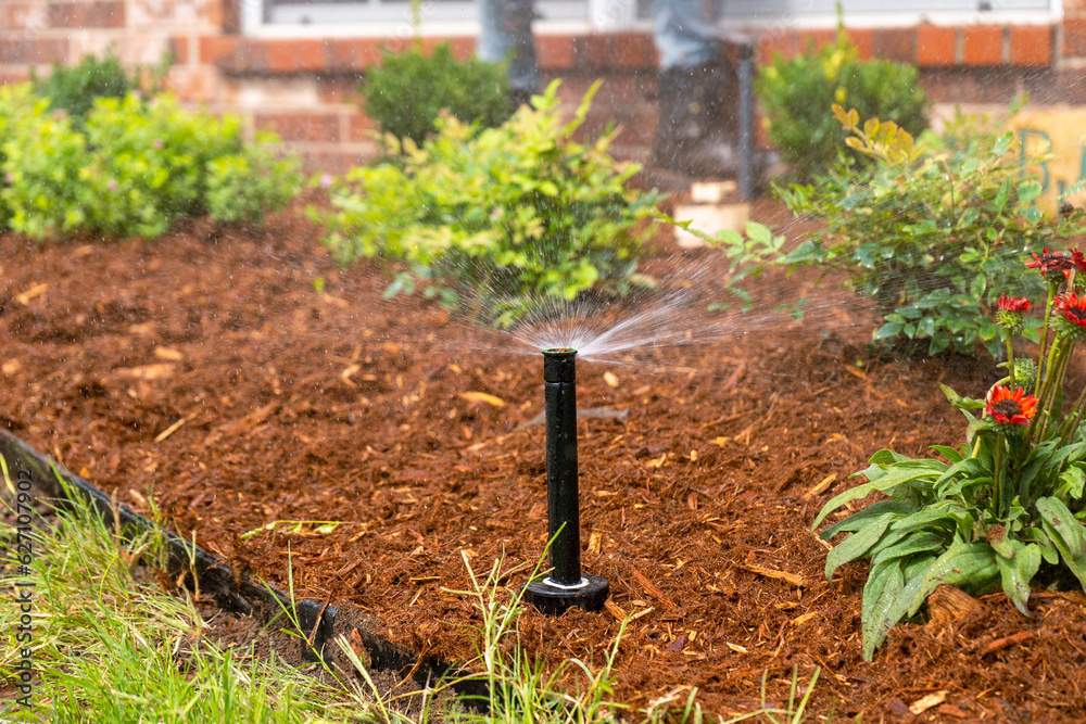 Landscaping Company Tending to A Front Lawn, Flower Bed Cutting Grass, Blowing Debris, and A Retaining Wall