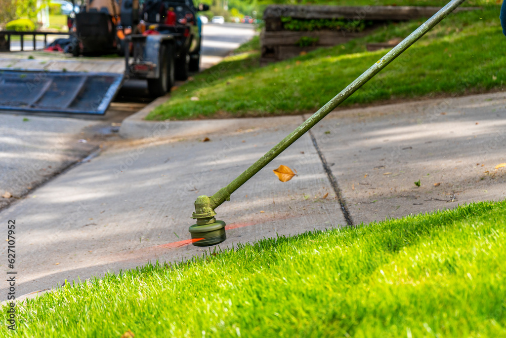 Landscaping Company Tending to A Front Lawn and Flower Bed Cutting Grass and Blowing Debris